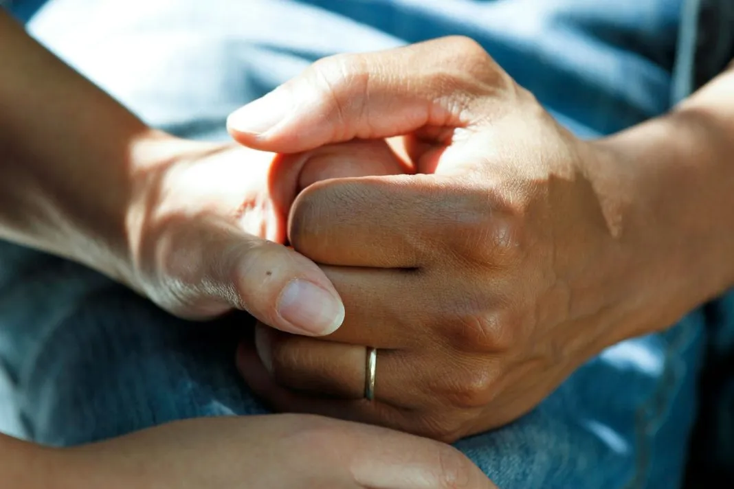 Les mains d’une aidante tiennent celles d’une personne âgée