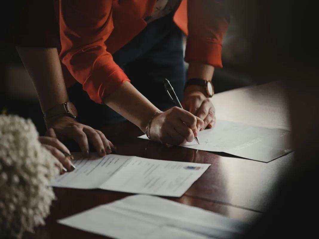 Une personne âgée relit un contrat posé sur une table, stylo à la main