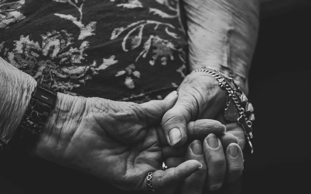 Une femme âgée tient la main d’une femme plus jeune