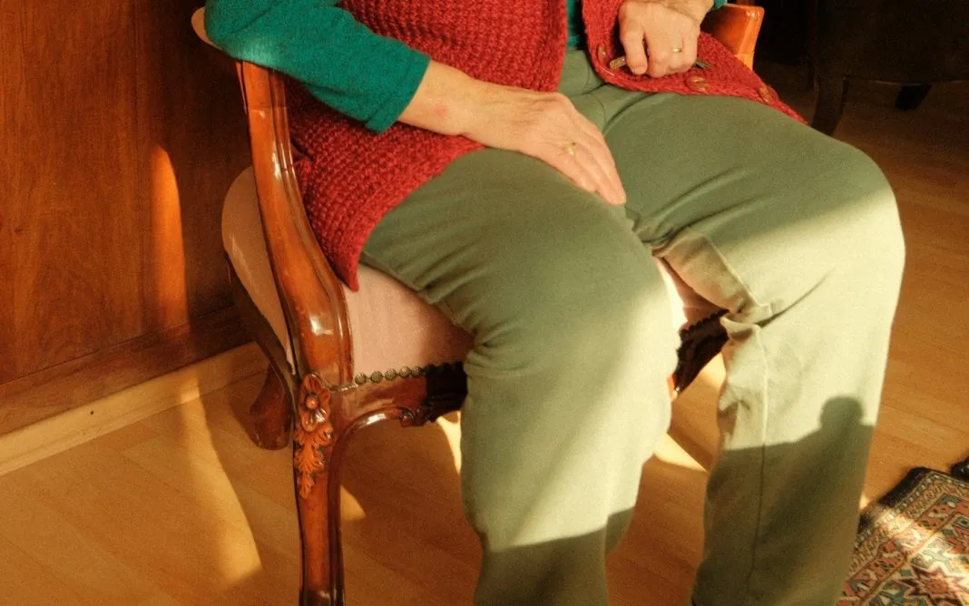Une femme âgée assise dans un fauteuil de son salon